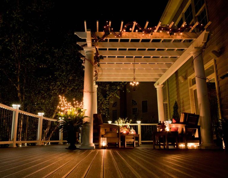 Why Choose Us - Outdoor deck at night with lights and white pergola