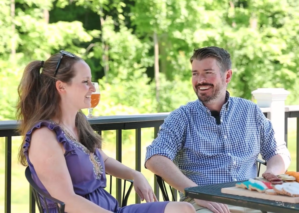 A smiling man and woman enjoying a conversation on a sunny balcony